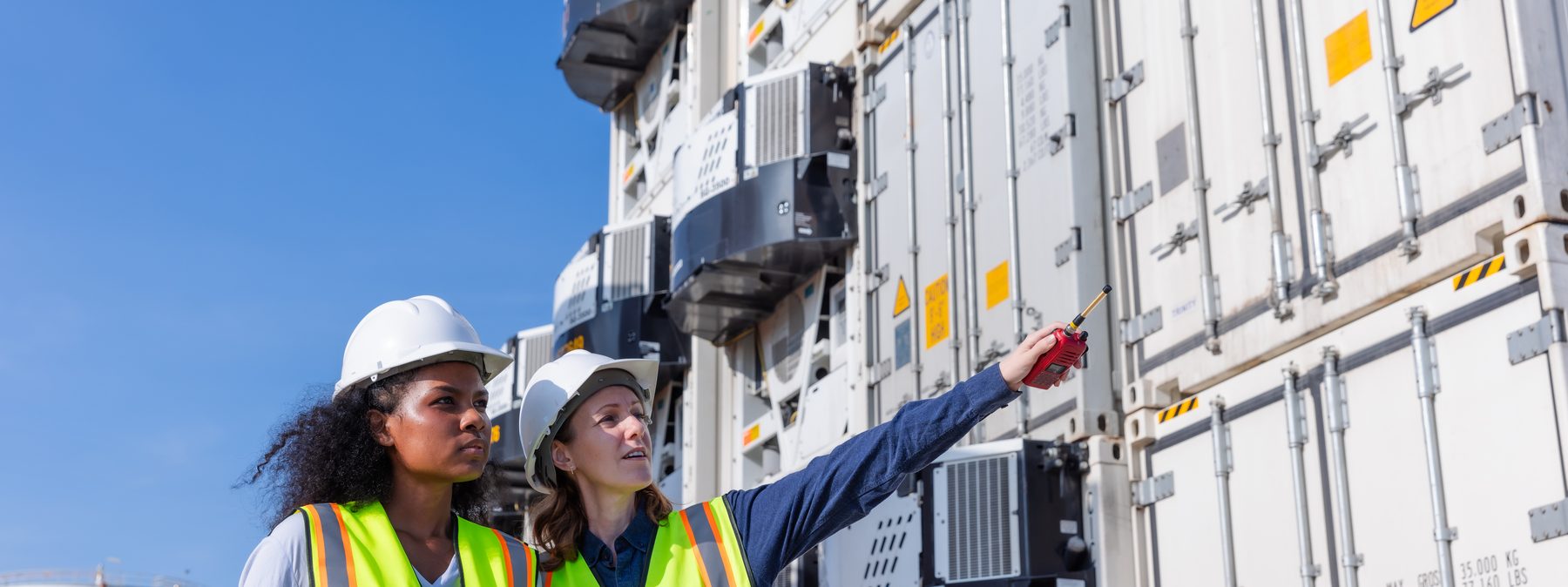 Two engineers in hard hats and high-visibility vests inspecting energy infrastructure at a working site.